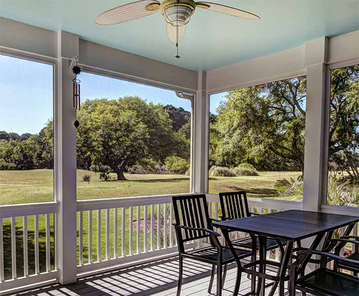 A screened-in porch with black table and chairs.